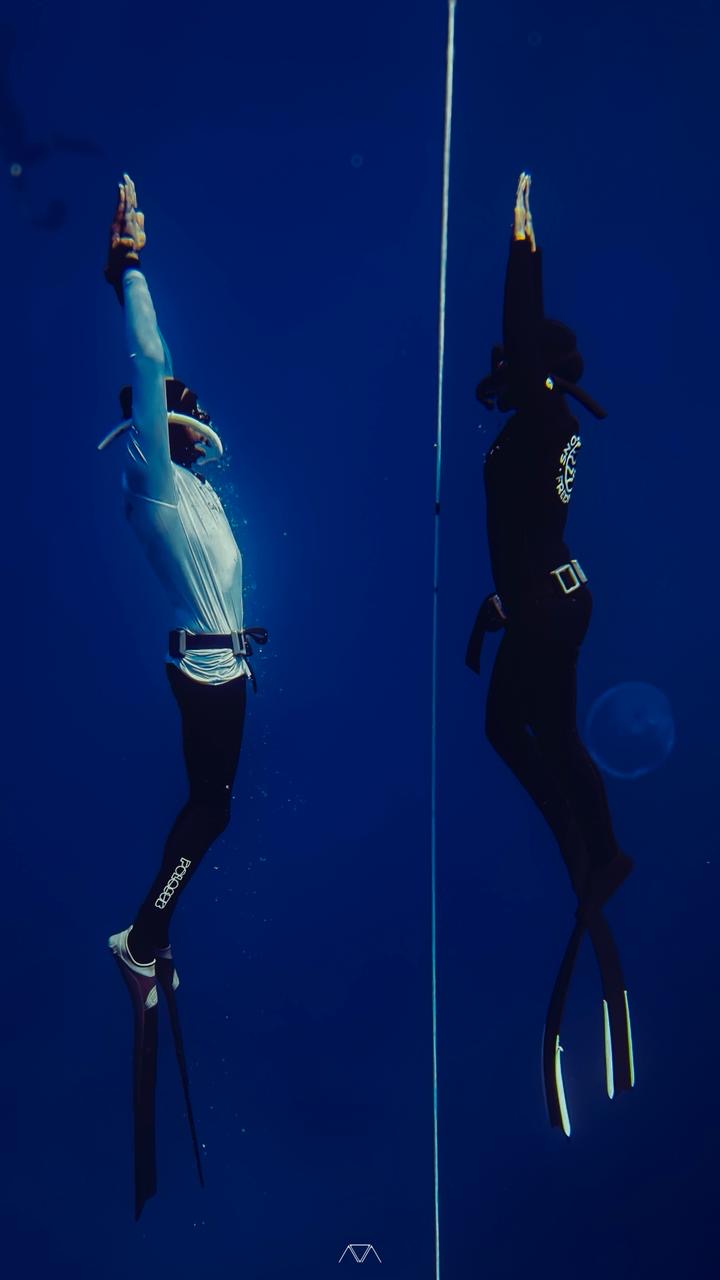 Two freedivers ascending in deep blue